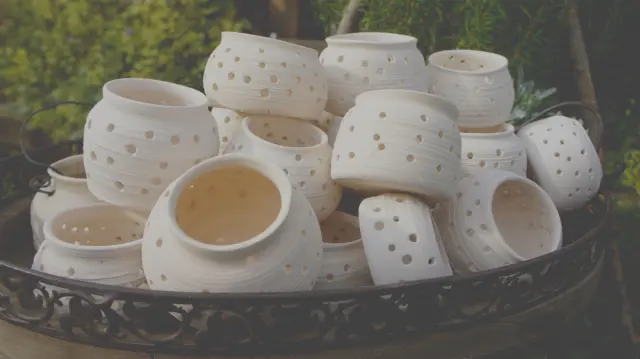 White pots with holes on a wrought-iron tray