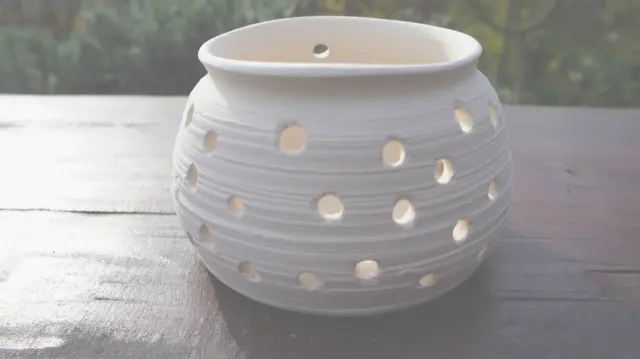 A white pot with holes on a garden table