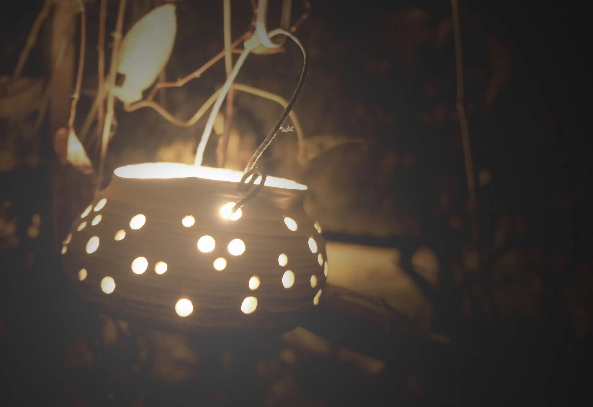 A candle pot glowing in the garden at dusk